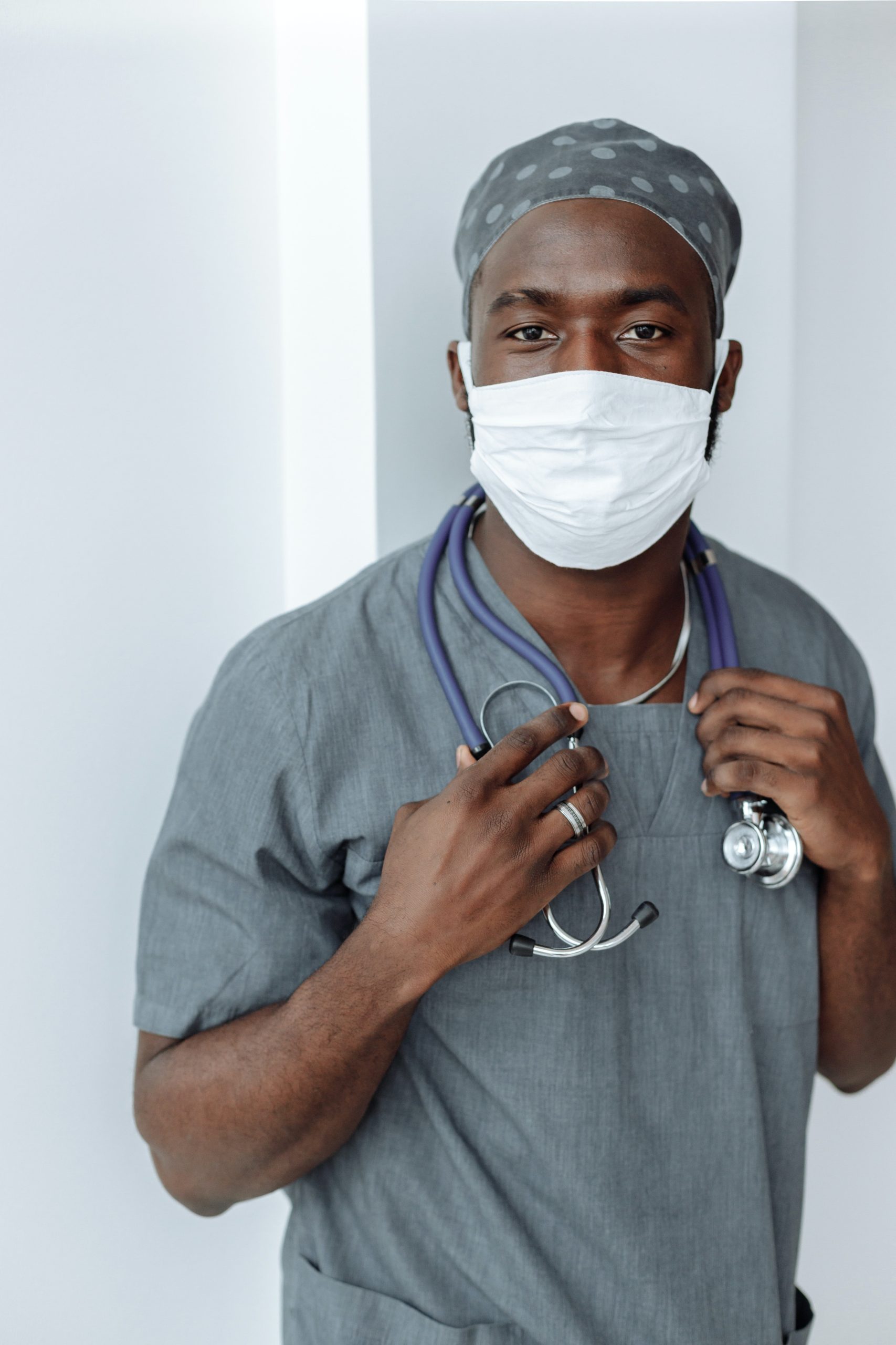 young Doctor in blue scrubs wearing a white face mask preparing to give a medical exam covered by health insurance